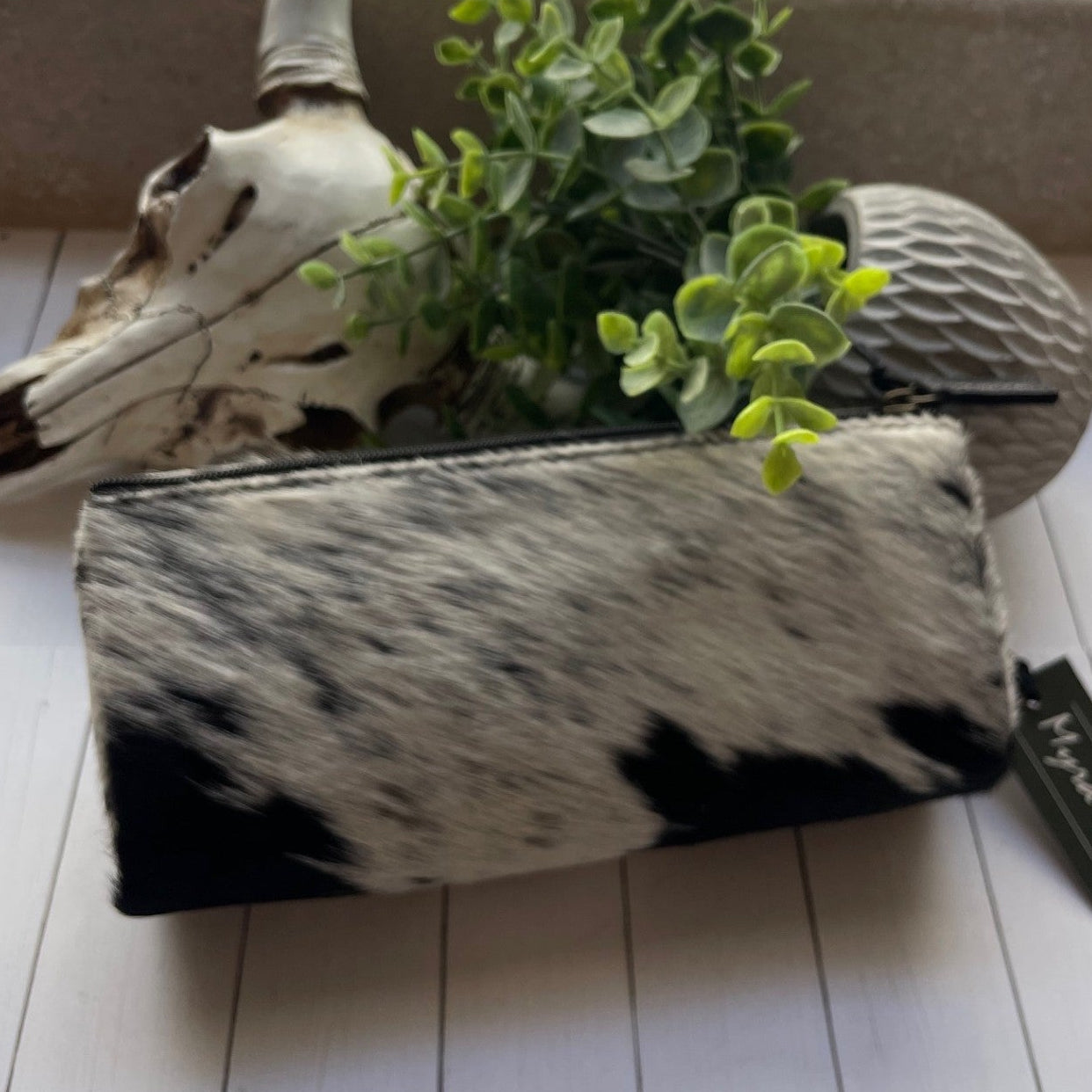 Cowhide pouch with plant and skull on a white surface