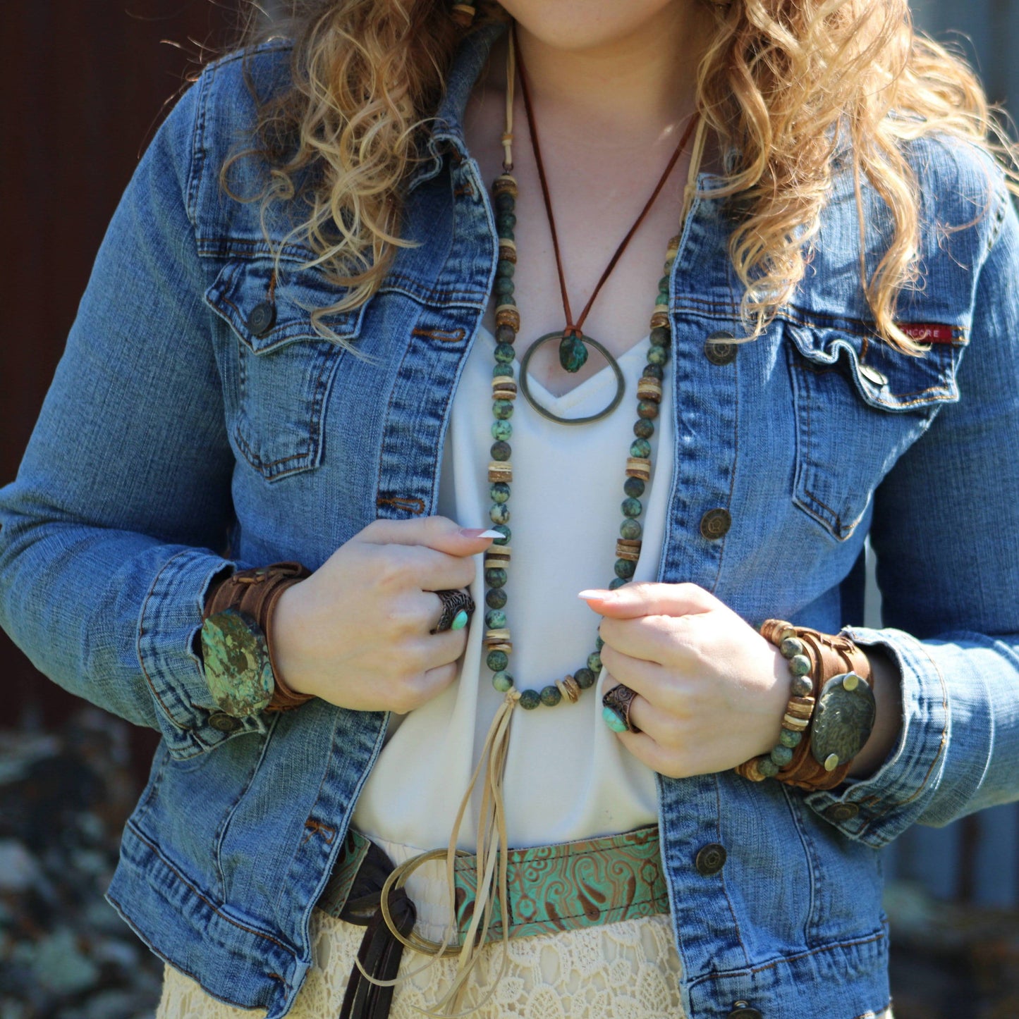Person wearing a denim jacket with a necklace and bracelets