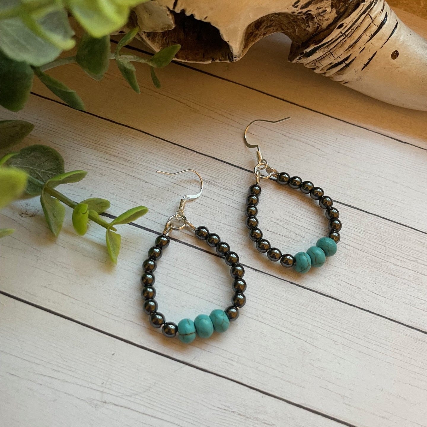 Pair of beaded earrings on a wooden surface with a natural background