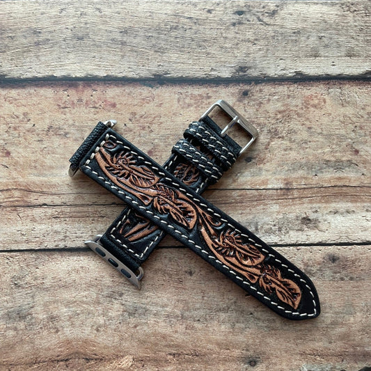 Tooled leather watch strap on a wooden surface