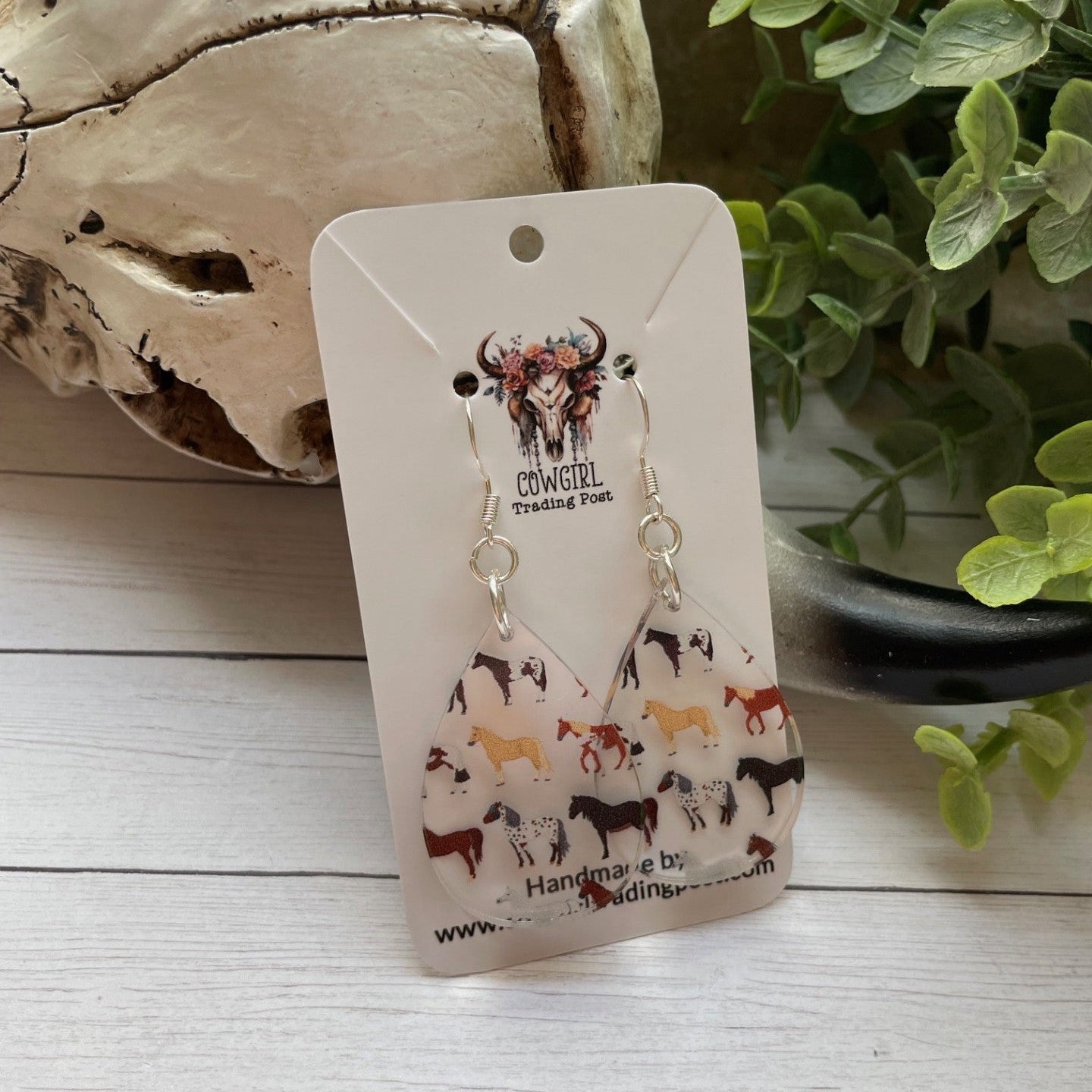 Earring card with earrings on a wooden surface with a plant in the background