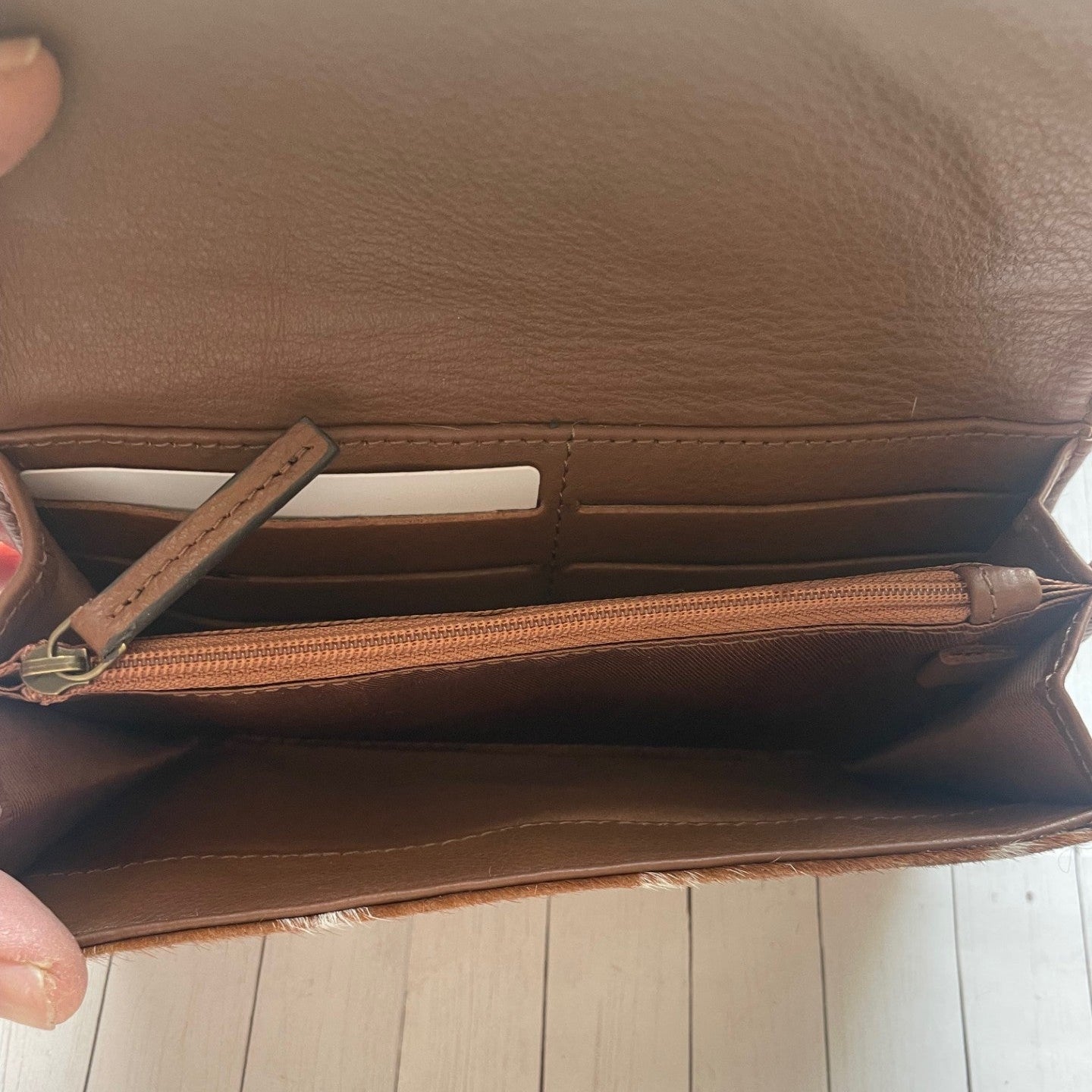 Brown leather wallet held open on a wooden surface