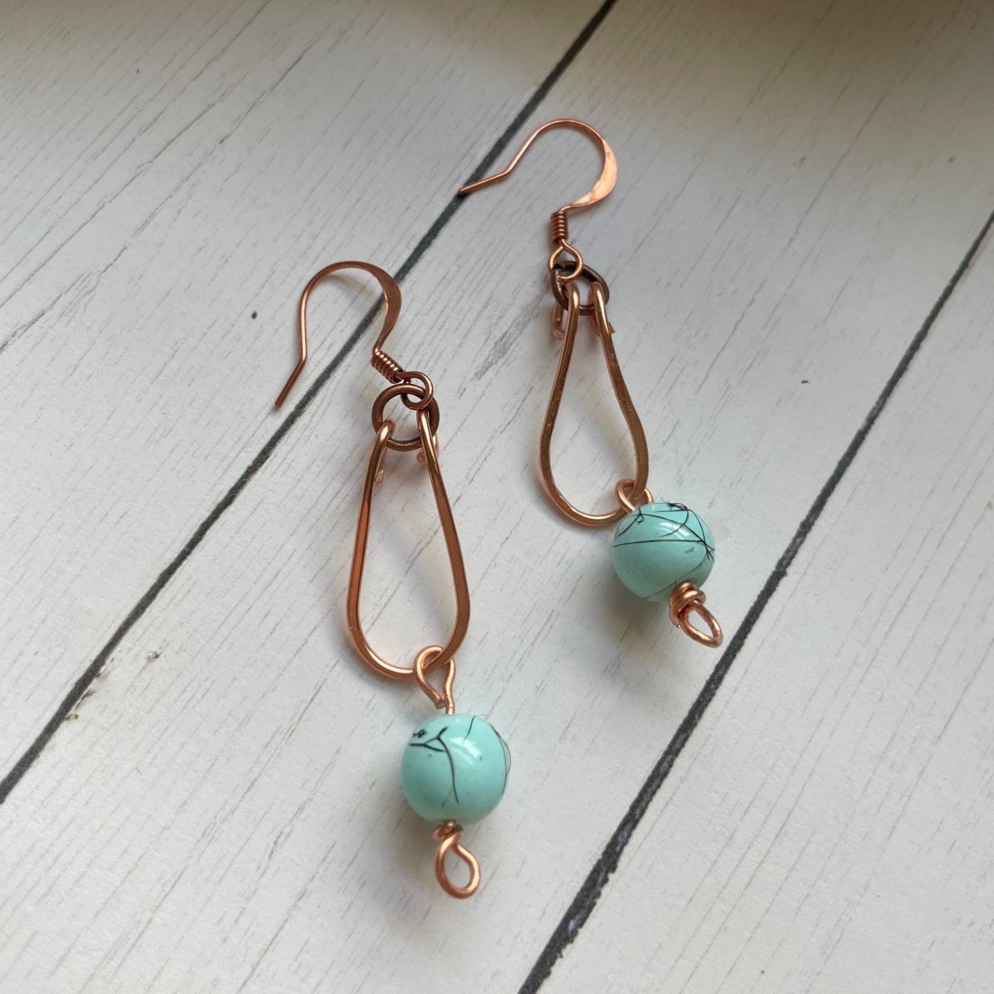 Copper Loop with a Turquoise colored bead hanging from copper colored earrings