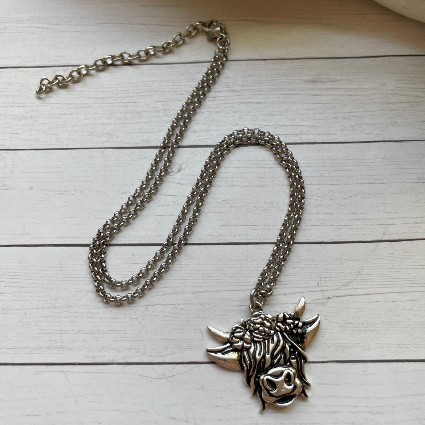Silver necklace with a detailed pendant on a wooden surface