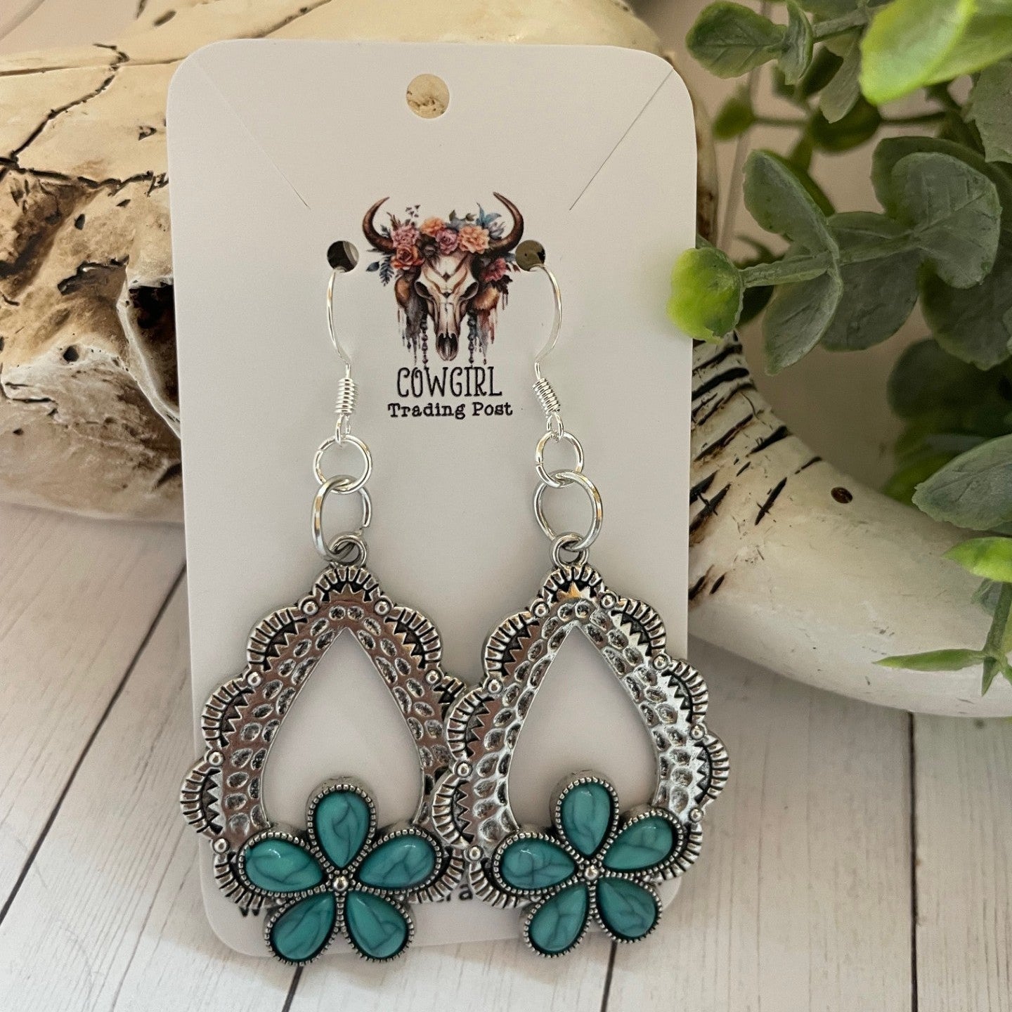 Pair of earrings with turquoise flowers on a display card with 'Cowgirl Trading Post' branding.