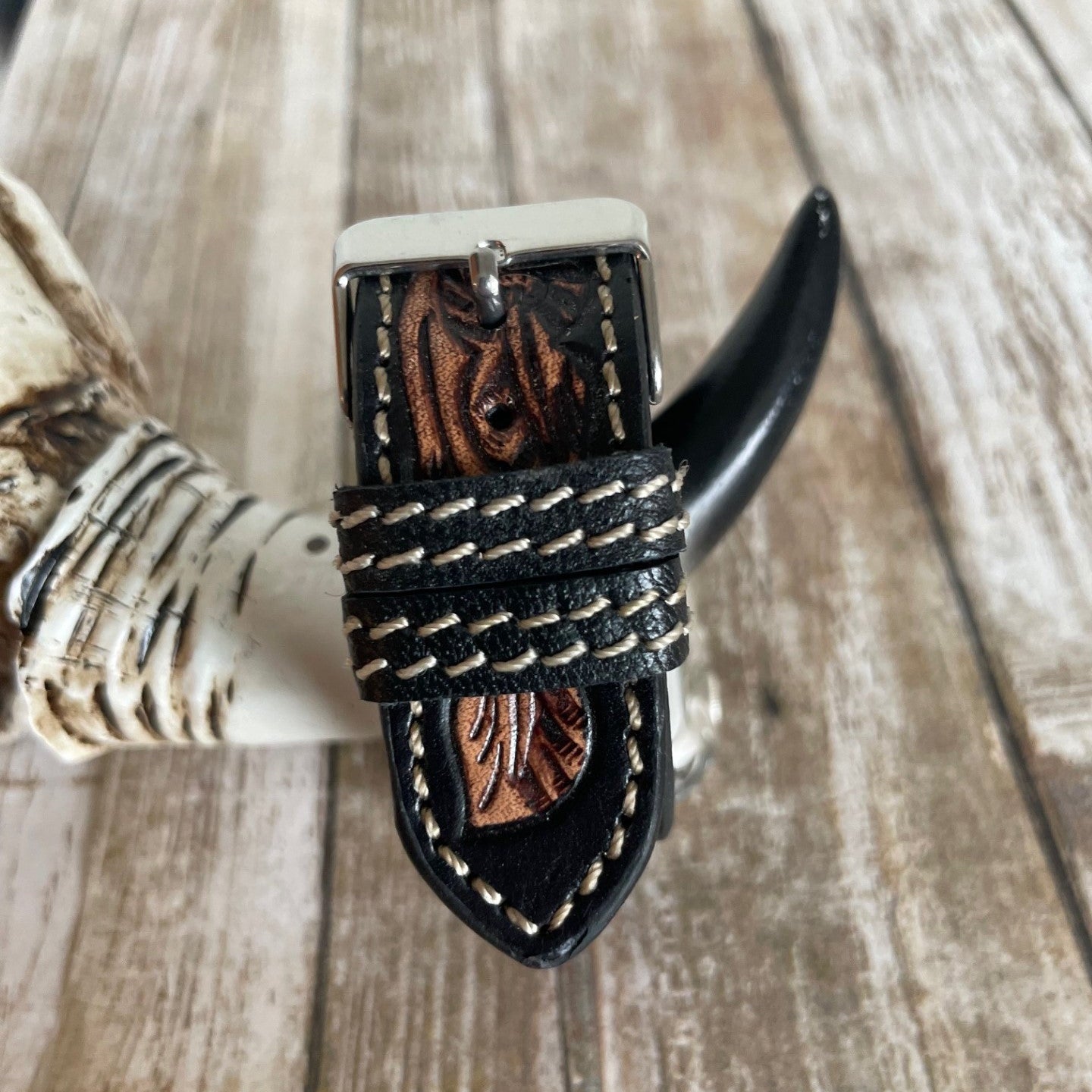 Black leather belt with braided design on a wooden surface