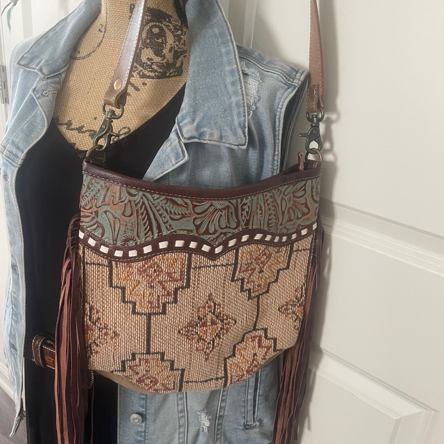 Decorative handbag with fringe on a mannequin against a white wall