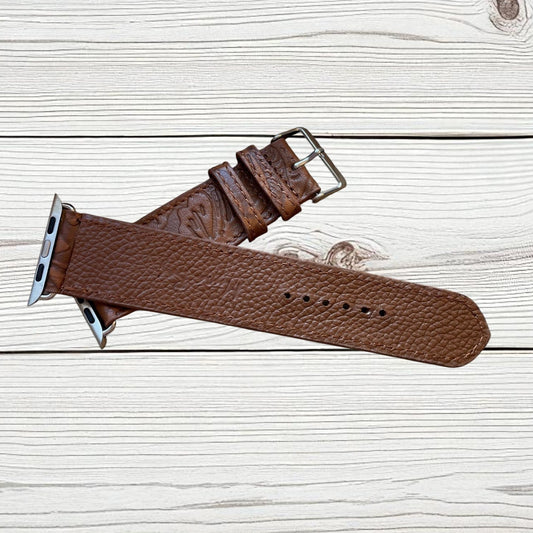 Brown leather watch strap on a light wooden surface
