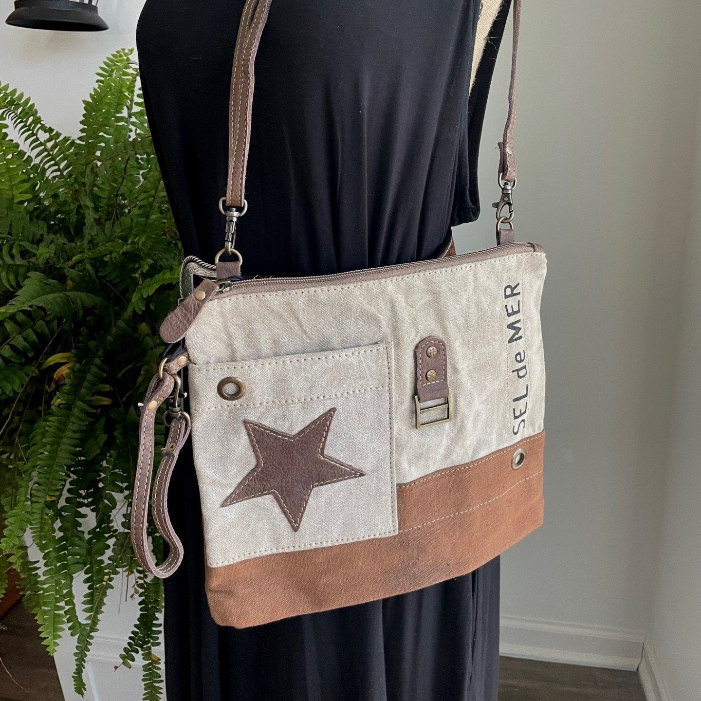 Mannequin wearing a black dress with a beige crossbody bag featuring a star design.