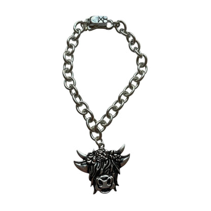 A silver-toned metal chain bracelet with a dark-finished gothic skull-and-fangs pendant, displayed on a plain white background.