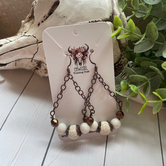 Copper chain and beads and white beads on a  cowgirl trading post earring card with a white cow or bull skull and greenery