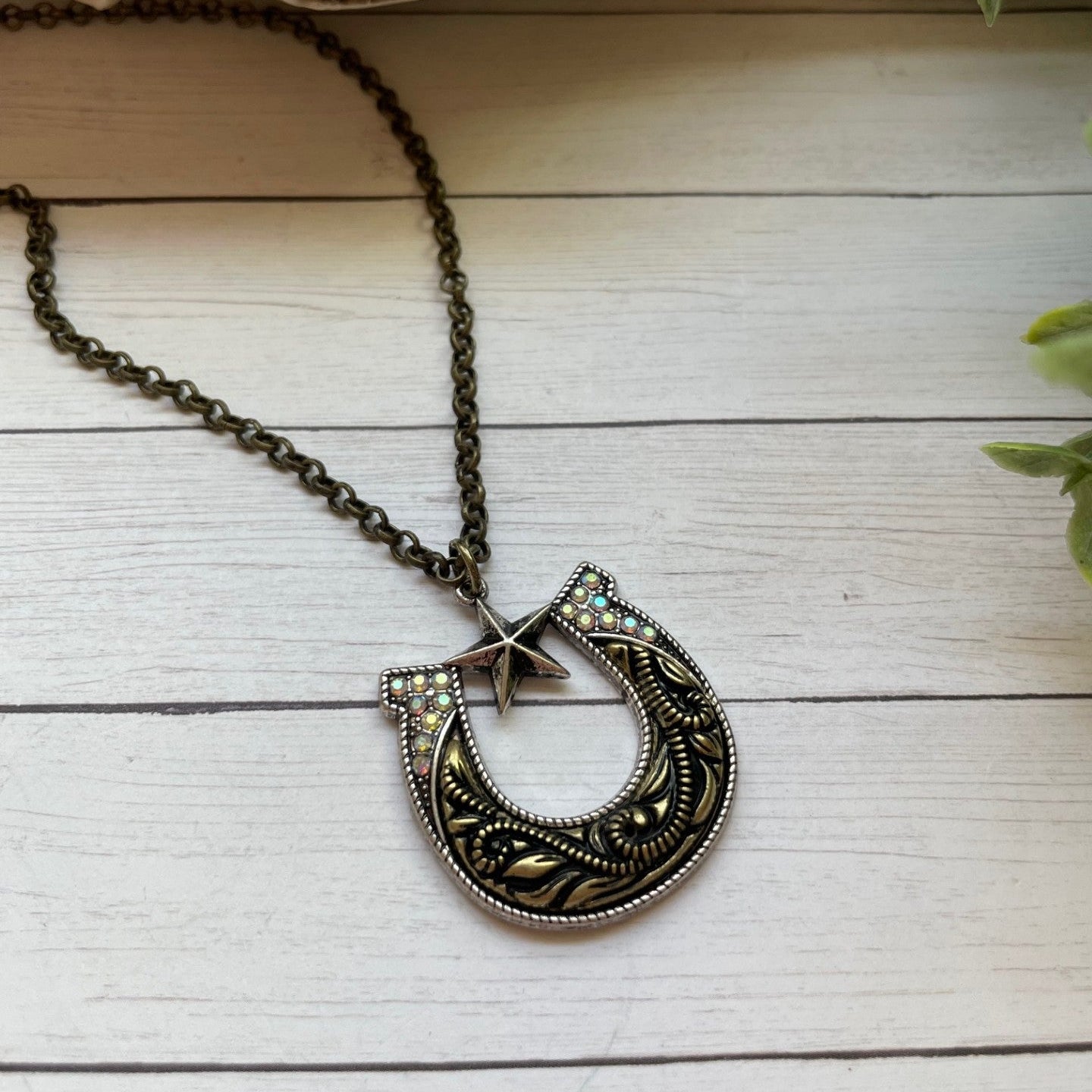 Decorative necklace with a detailed horseshoe and star pendant on a wooden surface