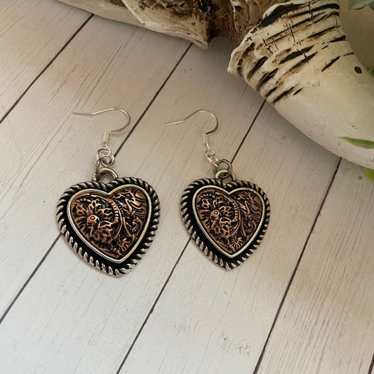 Heart-shaped earrings on a wooden surface with decorative elements.