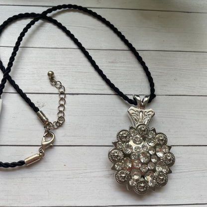 Bolo tie with decorative silver concho with sparkles clasp on a wooden surface