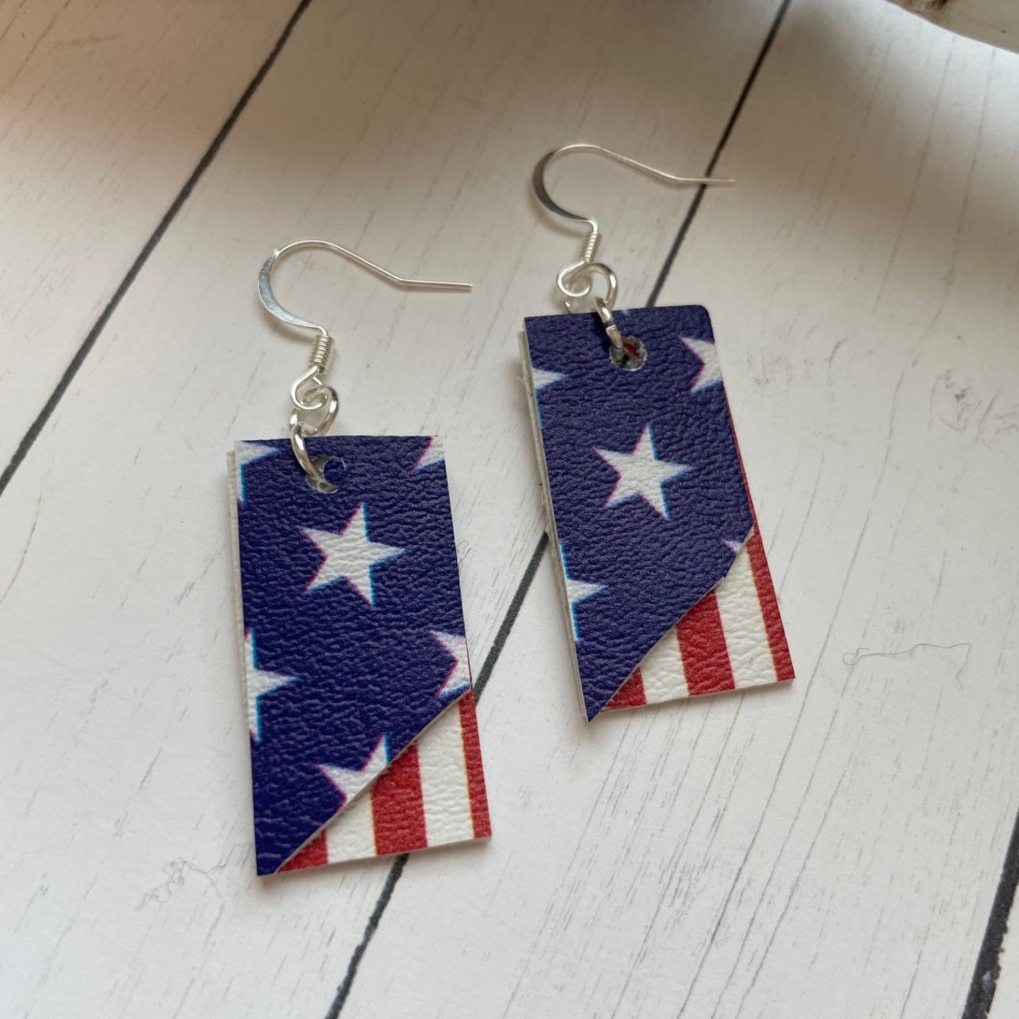 Pair of earrings with American flag design on a wooden surface