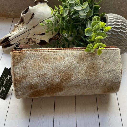 Cowhide planter with greenery and a deer skull on a white wooden surface