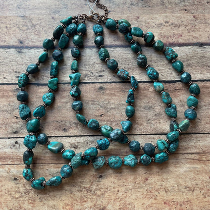 Turquoise beaded necklace on a wooden surface with a tag.