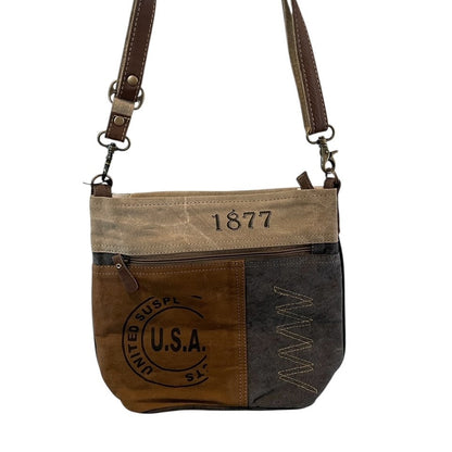 Brown and beige crossbody bag with '1877' and 'U.S.A.' text on a white background