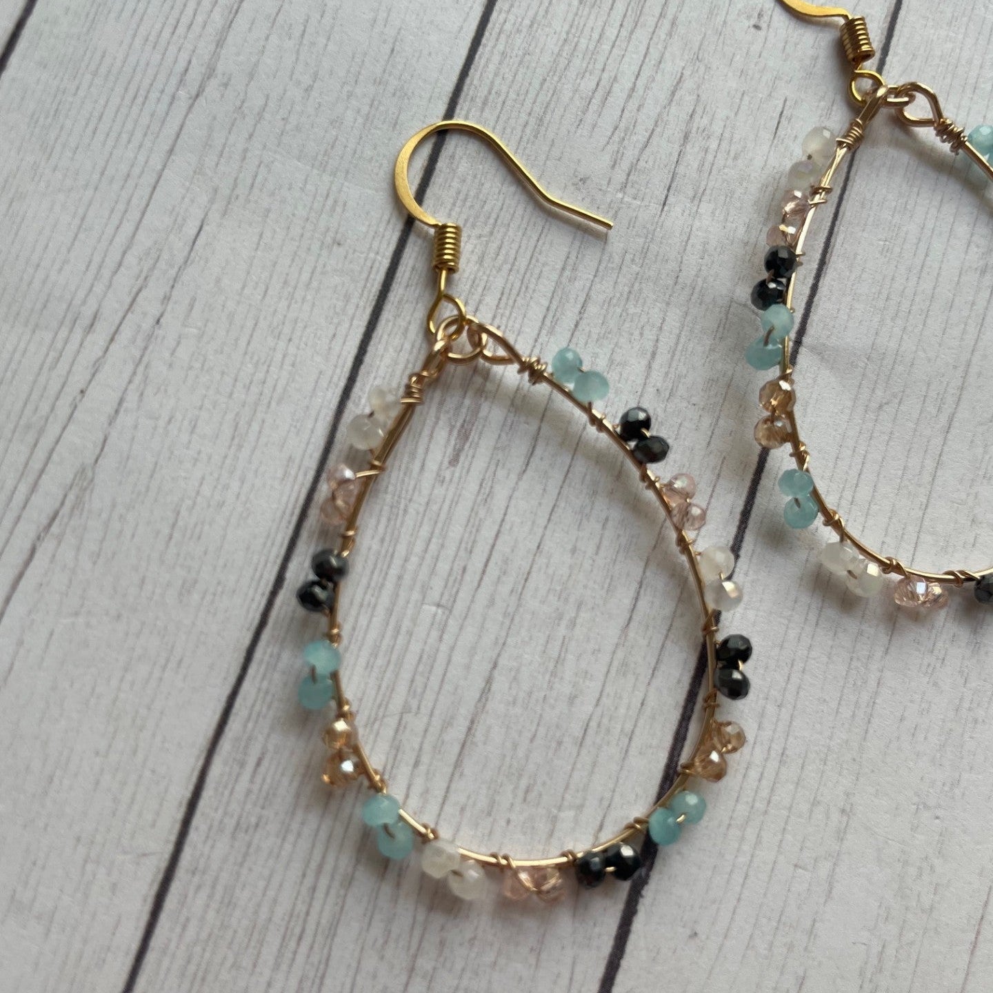Gold hoop earrings with beads on a wooden surface