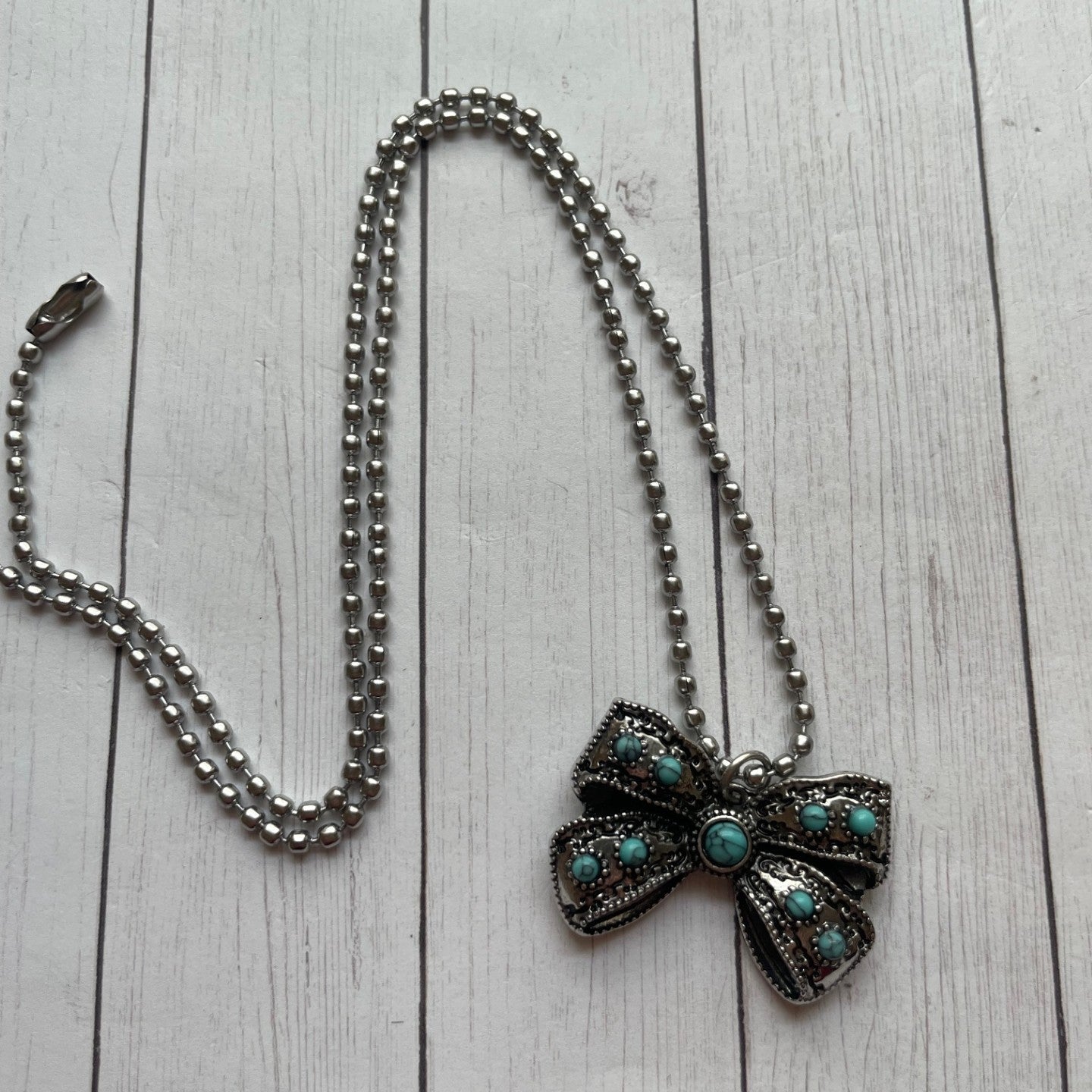 Necklace with a decorative bow pendant on a wooden surface