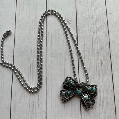 Necklace with a decorative bow pendant on a wooden surface