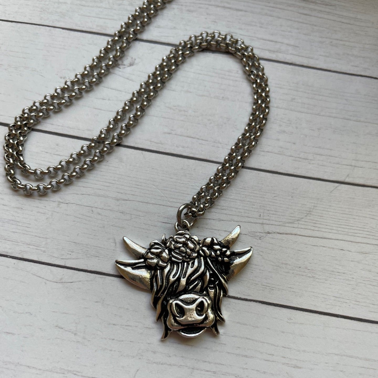 Silver necklace with a bull head pendant on a light wooden surface