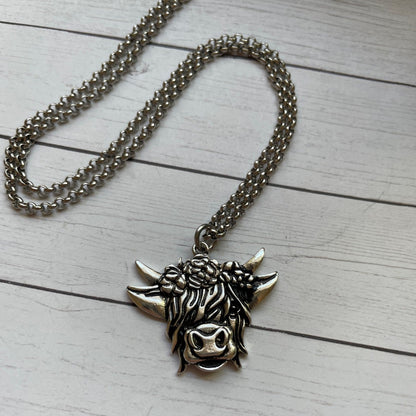 Silver necklace with a bull head pendant on a light wooden surface