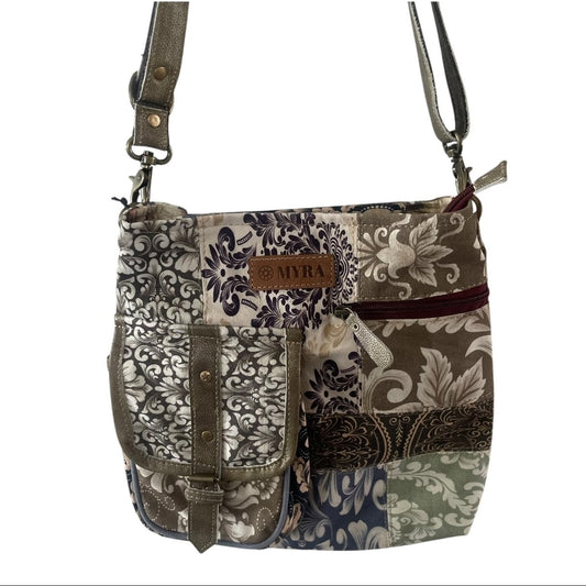 A patchwork crossbody handbag with multiple fabric panels featuring damask and paisley patterns in beige, brown, navy, and green, with olive green leather straps and hardware.