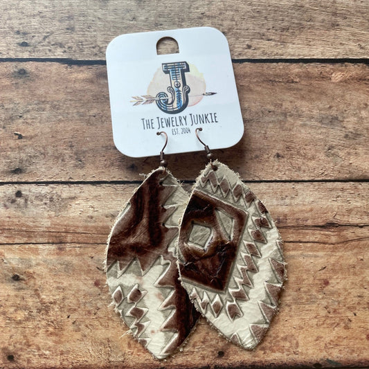Pair of silver studded earrings on a wooden surface with a branded card.