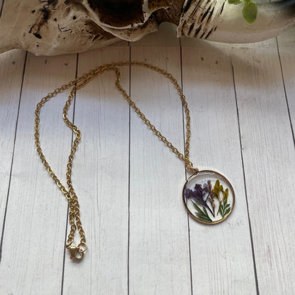 Necklace with a pendant featuring pressed flowers on a wooden surface