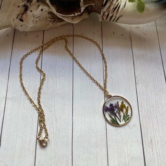 Necklace with a pendant featuring pressed flowers on a wooden surface