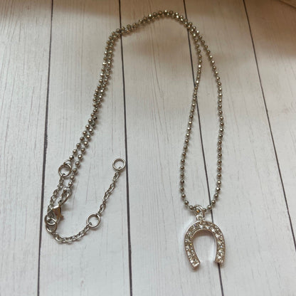 Silver necklace with a horseshoe pendant on a wooden surface