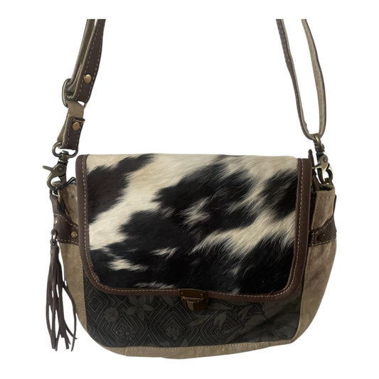A shoulder bag featuring a black and white cowhide pattern on the front flap, brown leather trim, a patterned dark brown lower panel, and a matching brown shoulder strap, shown against a plain white background.