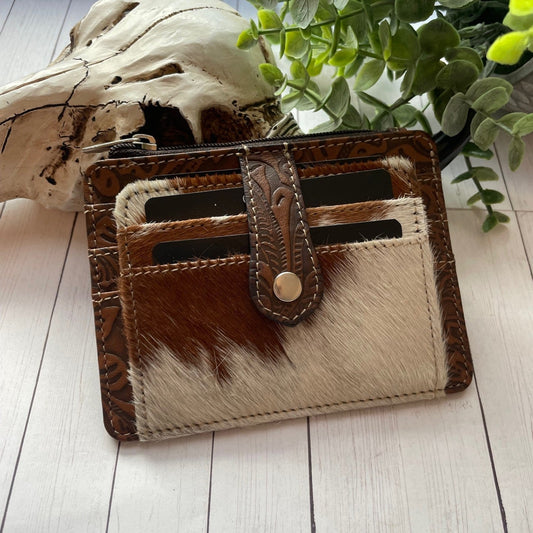 Black and white cowhide and leather wallet with a snap closure and credit card slots