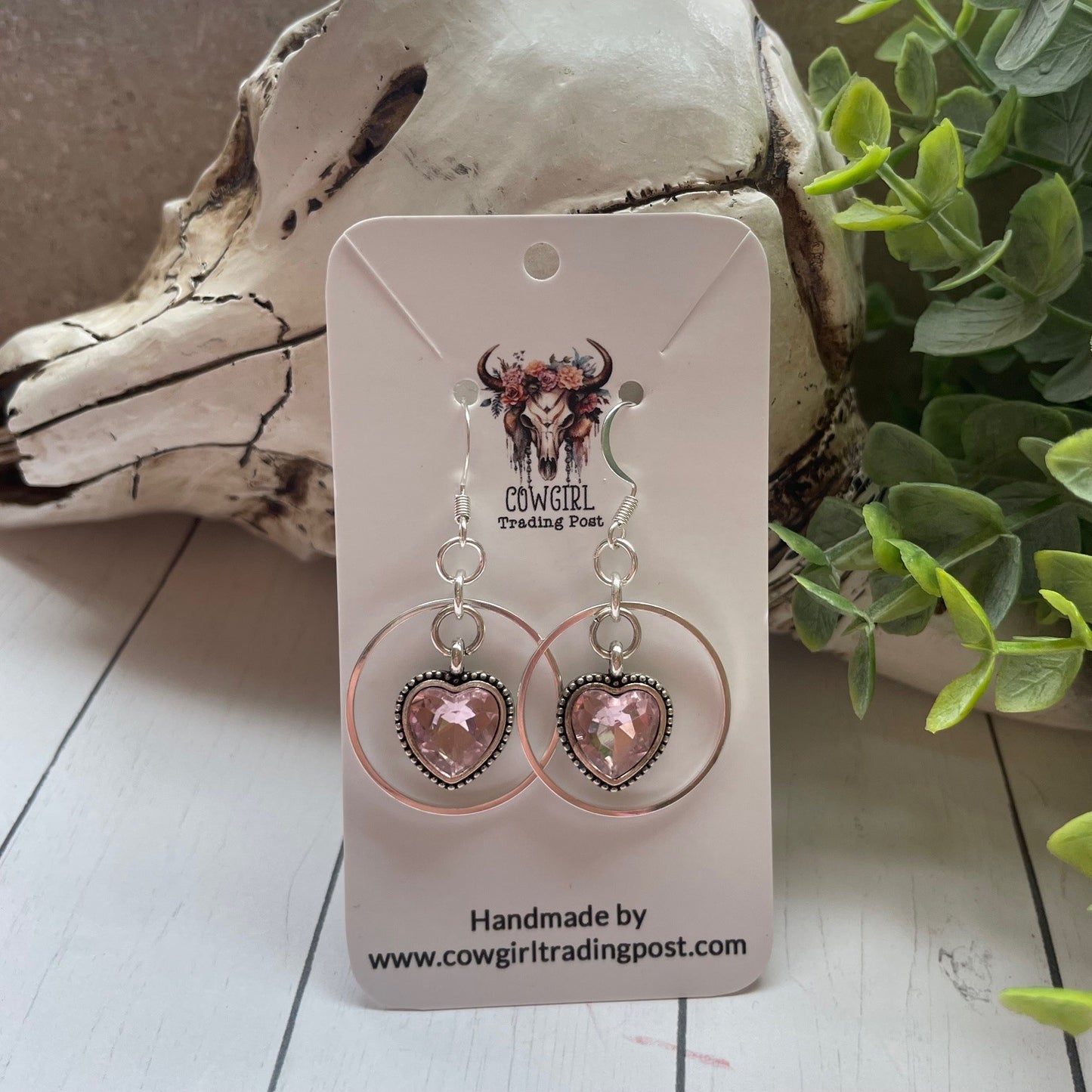 Pink sparky hearts with a silver ring around them earrings on a white wood background