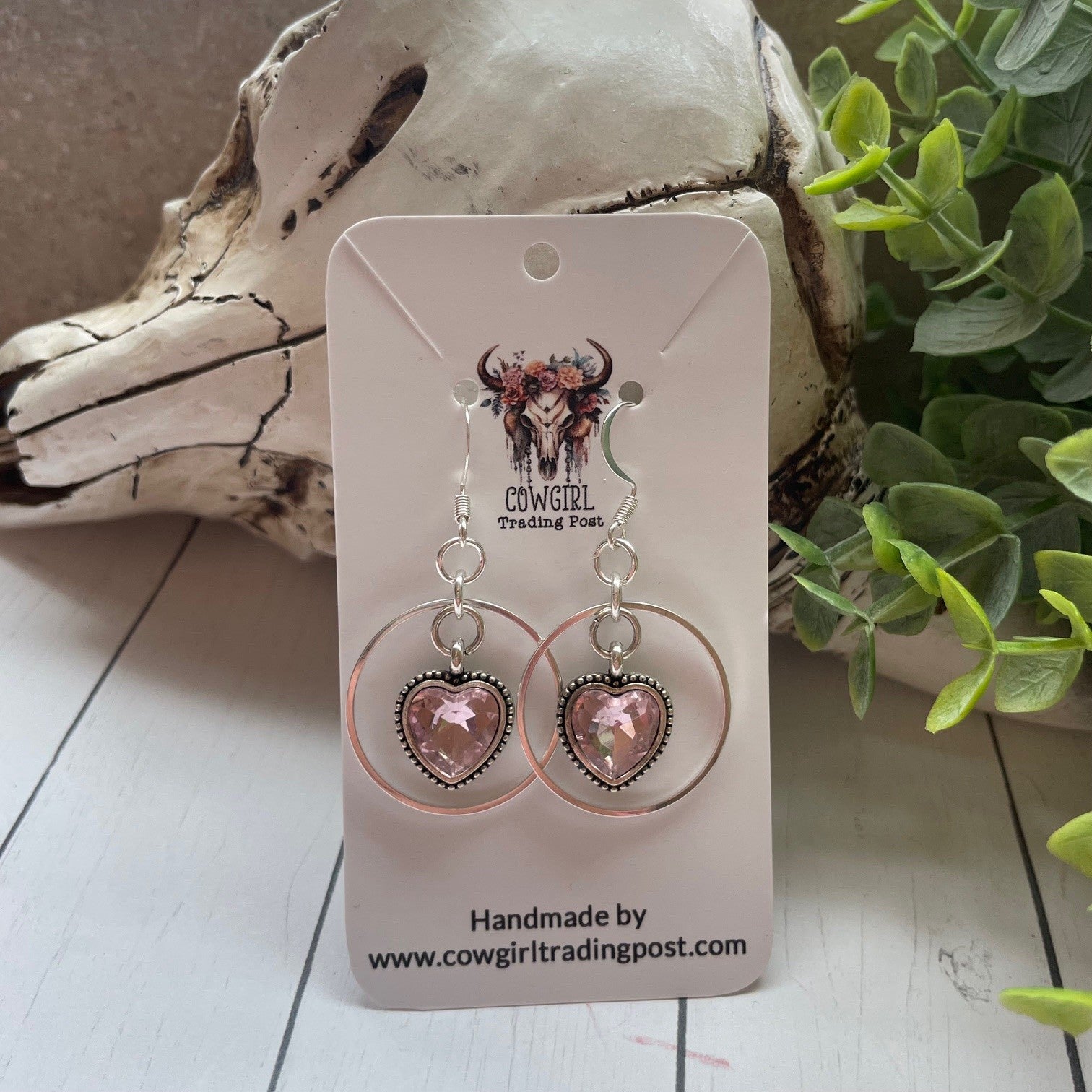 Pink sparky hearts with a silver ring around them earrings on a white wood background