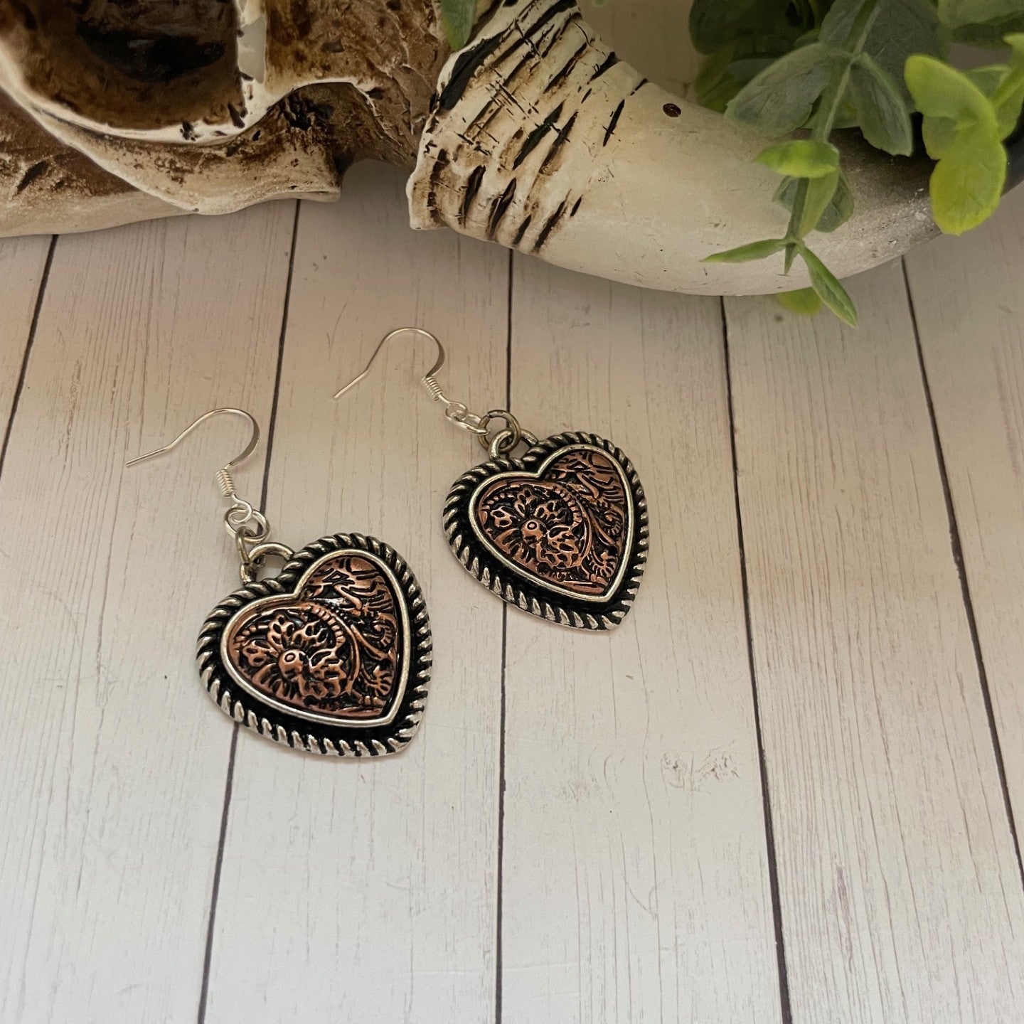 Heart-shaped earrings on a wooden surface with a natural background