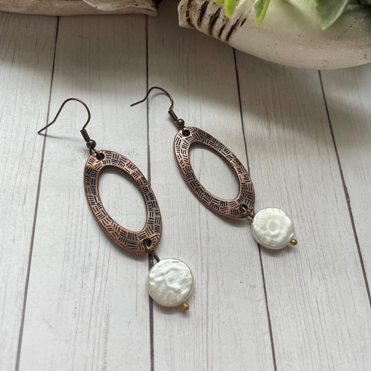 Pair of earrings with intricate designs on a wooden surface