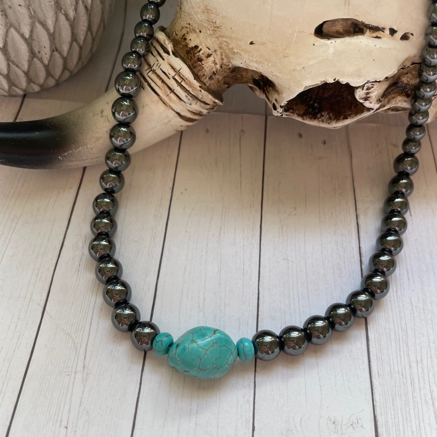 Necklace with turquoise bead on a skull and wooden surface
