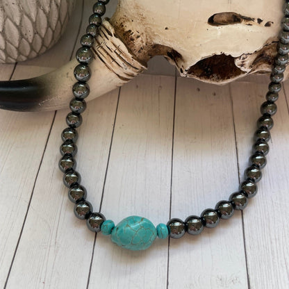 Necklace with turquoise bead on a skull and wooden surface