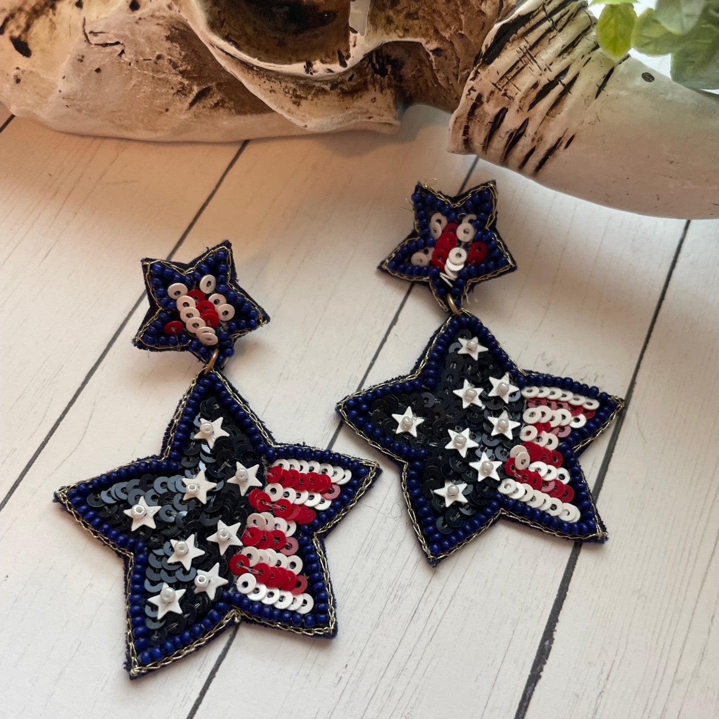 Star-shaped earrings with American flag design on a wooden surface