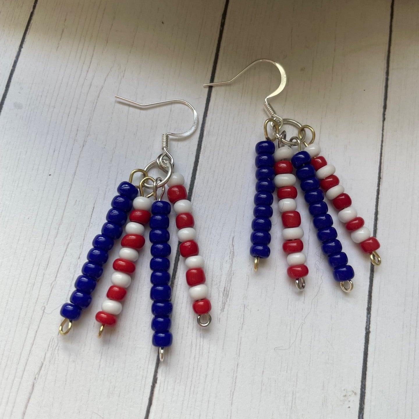 Pair of beaded earrings with red, white, and blue beads on a wooden surface.