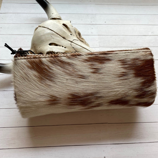 Clutch bag with cowhide pattern on a wooden surface