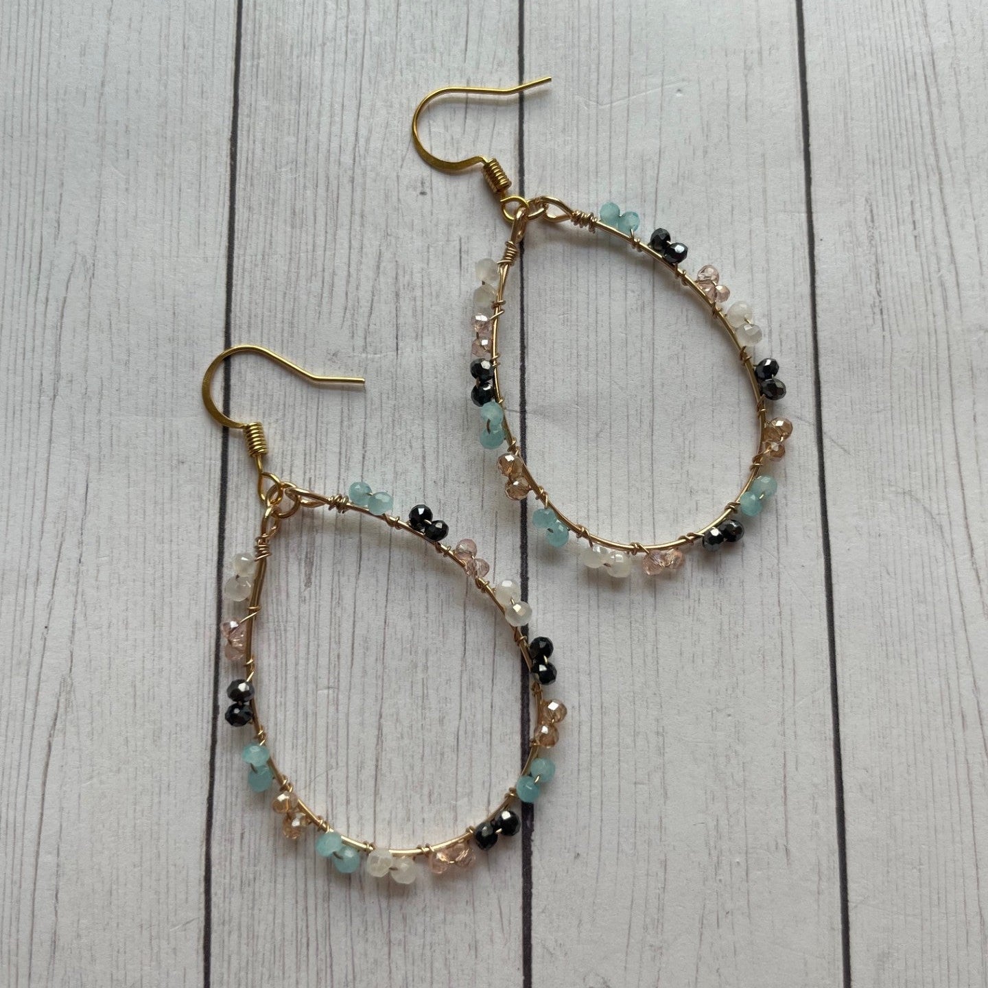 Pair of beaded hoop earrings on a wooden surface