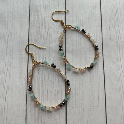 Pair of beaded hoop earrings on a wooden surface