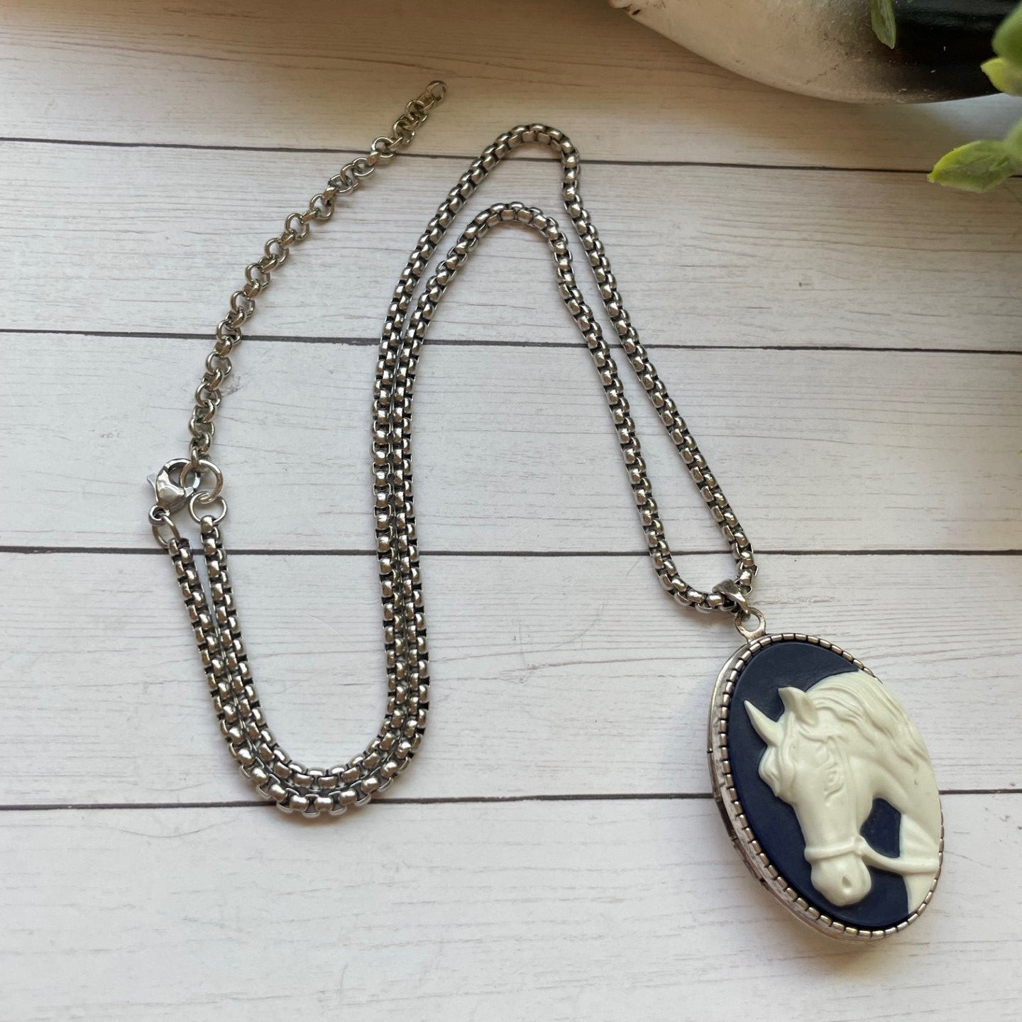 Necklace with a pendant featuring a horse design on a wooden surface.