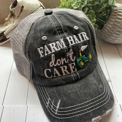 Gray cap with 'Farm Hair Don't Care' text and tractor graphic on a wooden surface.