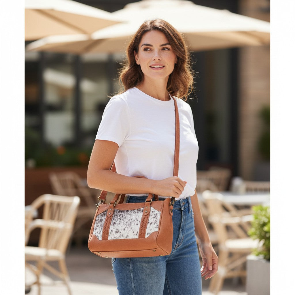 Woman holding a brown handbag with a floral pattern, standing outdoors.