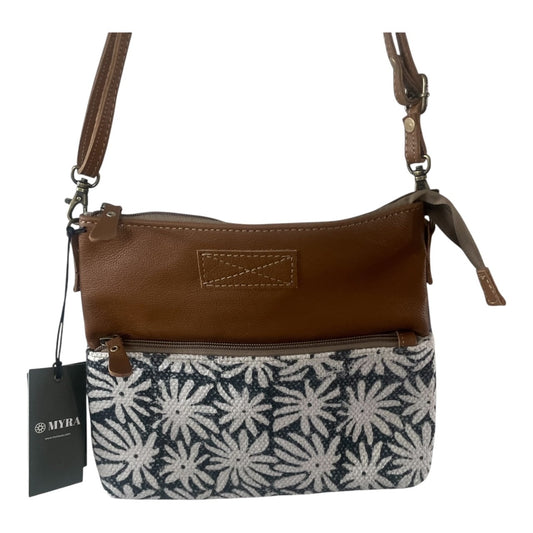 A brown leather crossbody bag with a black and white floral patterned fabric lower half, featuring a hanging black tag with the brand name 'MYRA'.