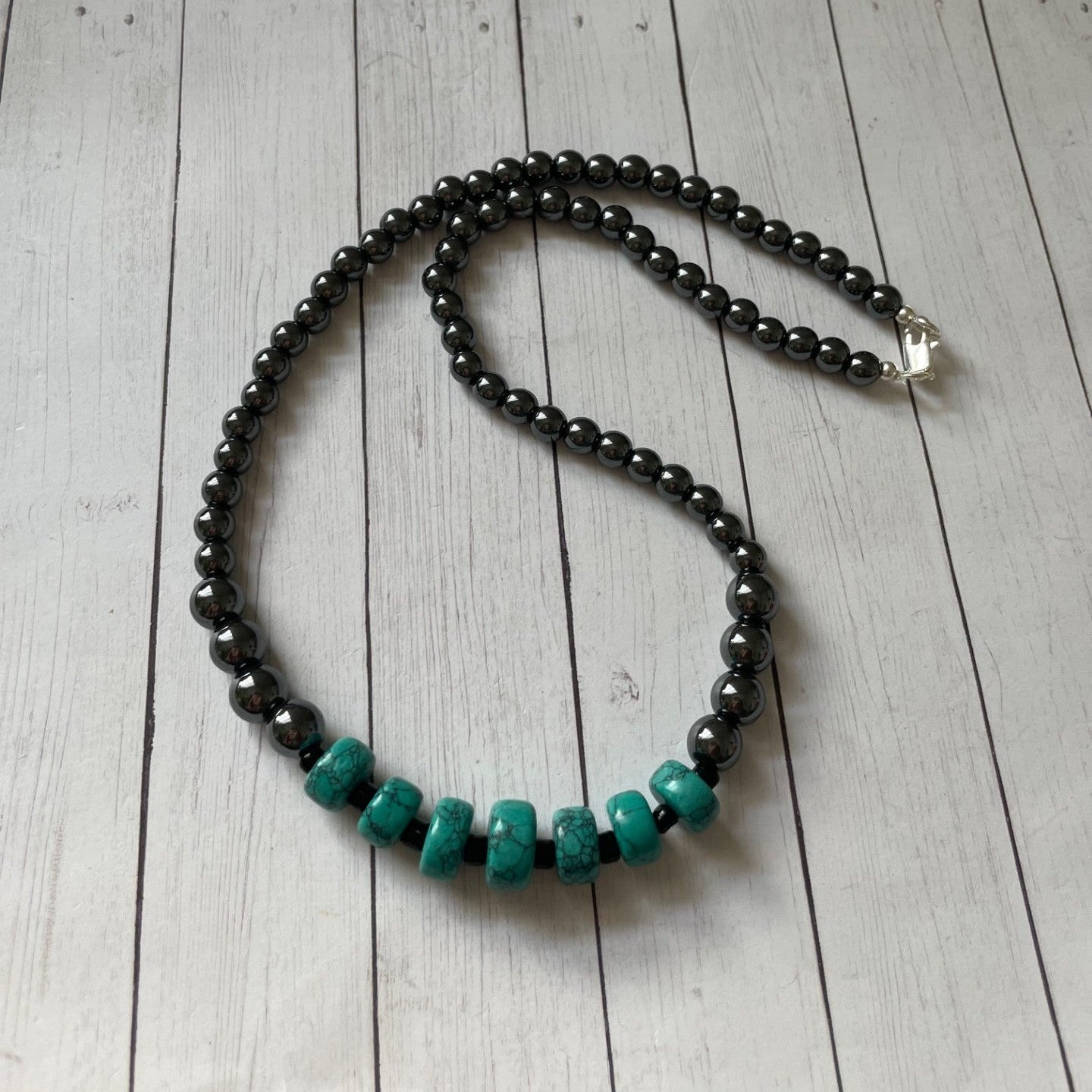 Necklace with black and turquoise beads on a wooden surface